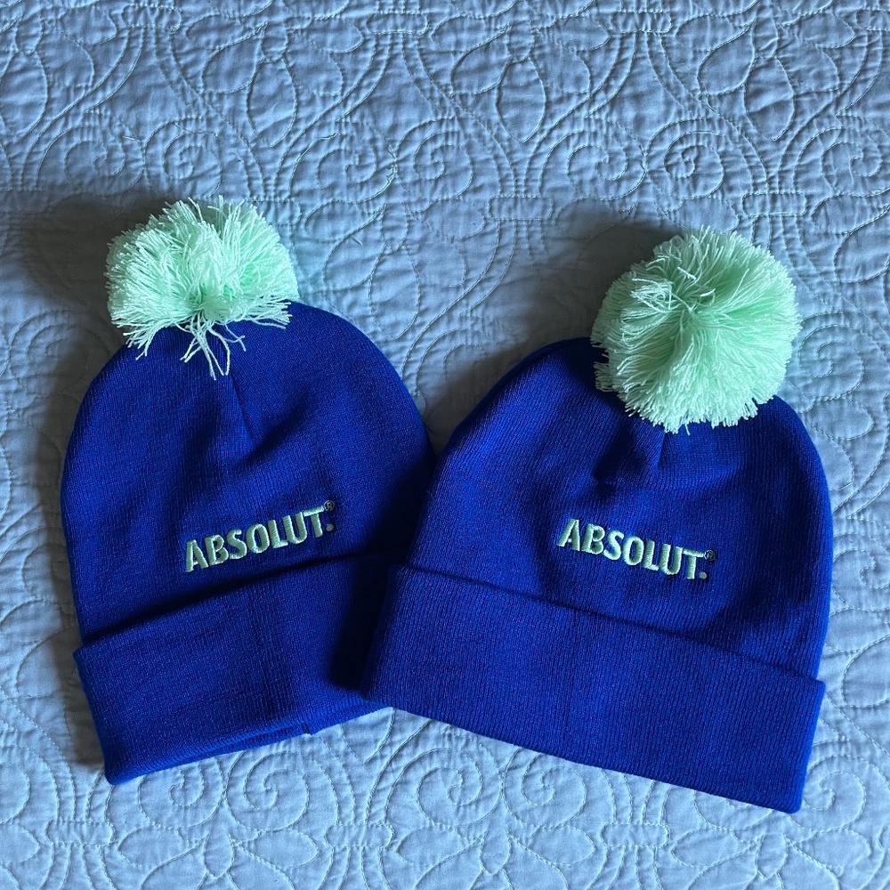 Two Blue beanies with green pom-pom